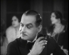 Scene from the Film 'Champagne': a Male Actor in a Nightclub Smoking a Cigarette, 1920s. Creator: British Pathe Ltd.