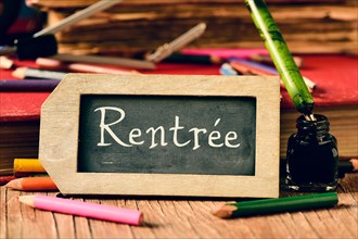 label-shaped chalkboard with the text rentree, back to school in french, some old books and old stationery such as a pen nib or